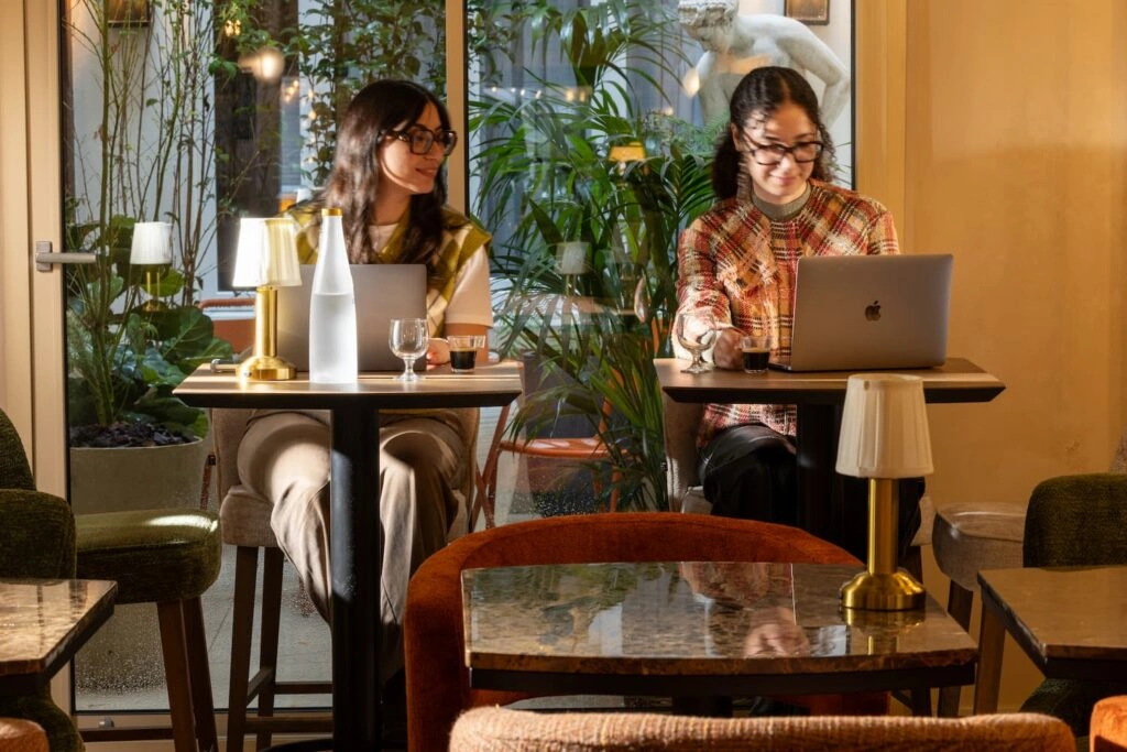 Personnes travaillant sur ordinateur portable dans le bar-lounge végétalisé de l'Hôtel des Deux Continents