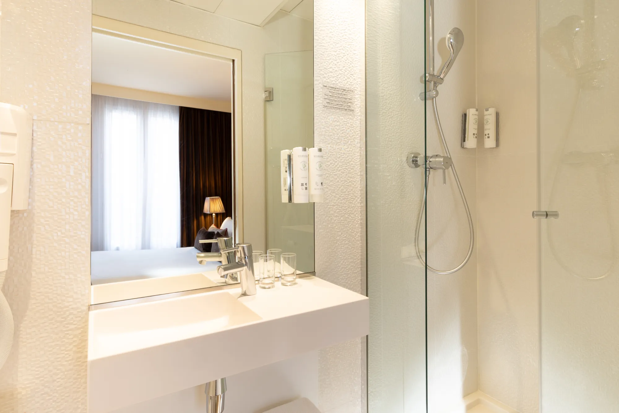 Vasque blanche et douche vitrée à double pommeau dans la salle de bain de la chambre Classique de l'Hôtel des Deux Continents