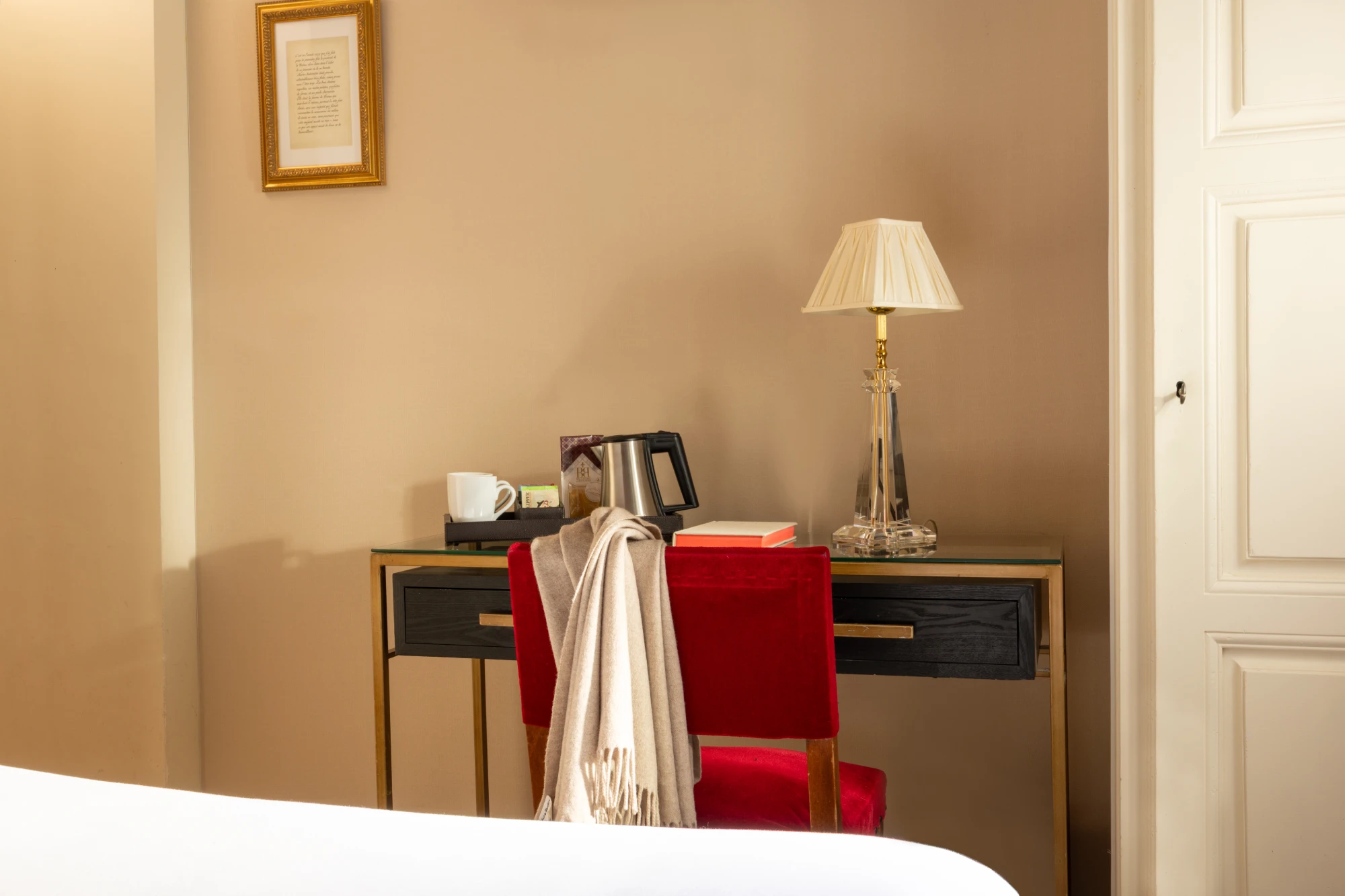 Bureau avec chaise en velours rouge et plateau de courtoisie dans la chambre Cosy de l'Hôtel des Deux Continents
