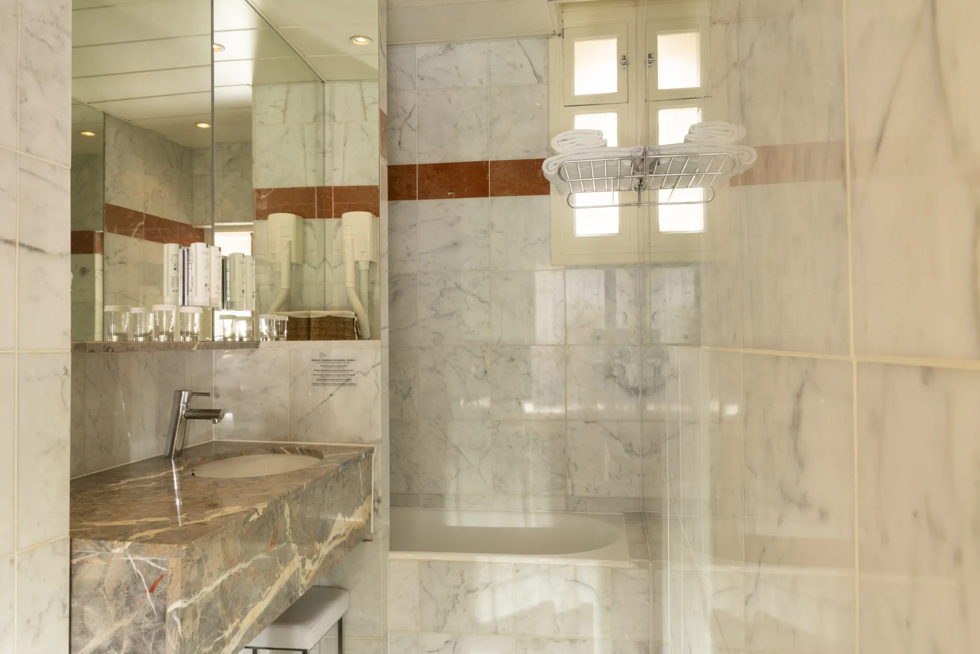 Salle de bain en marbre avec espace bain-douche vitré dans la chambre Deluxe de l'Hôtel des Deux Continents