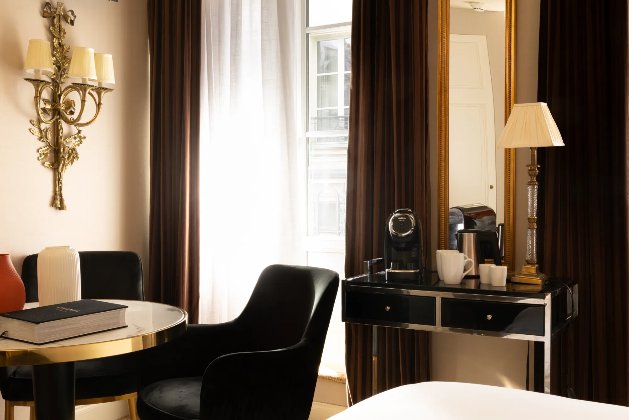 Bureau noir avec lampe et fauteuil de velours près de la fenêtre dans la chambre Deluxe