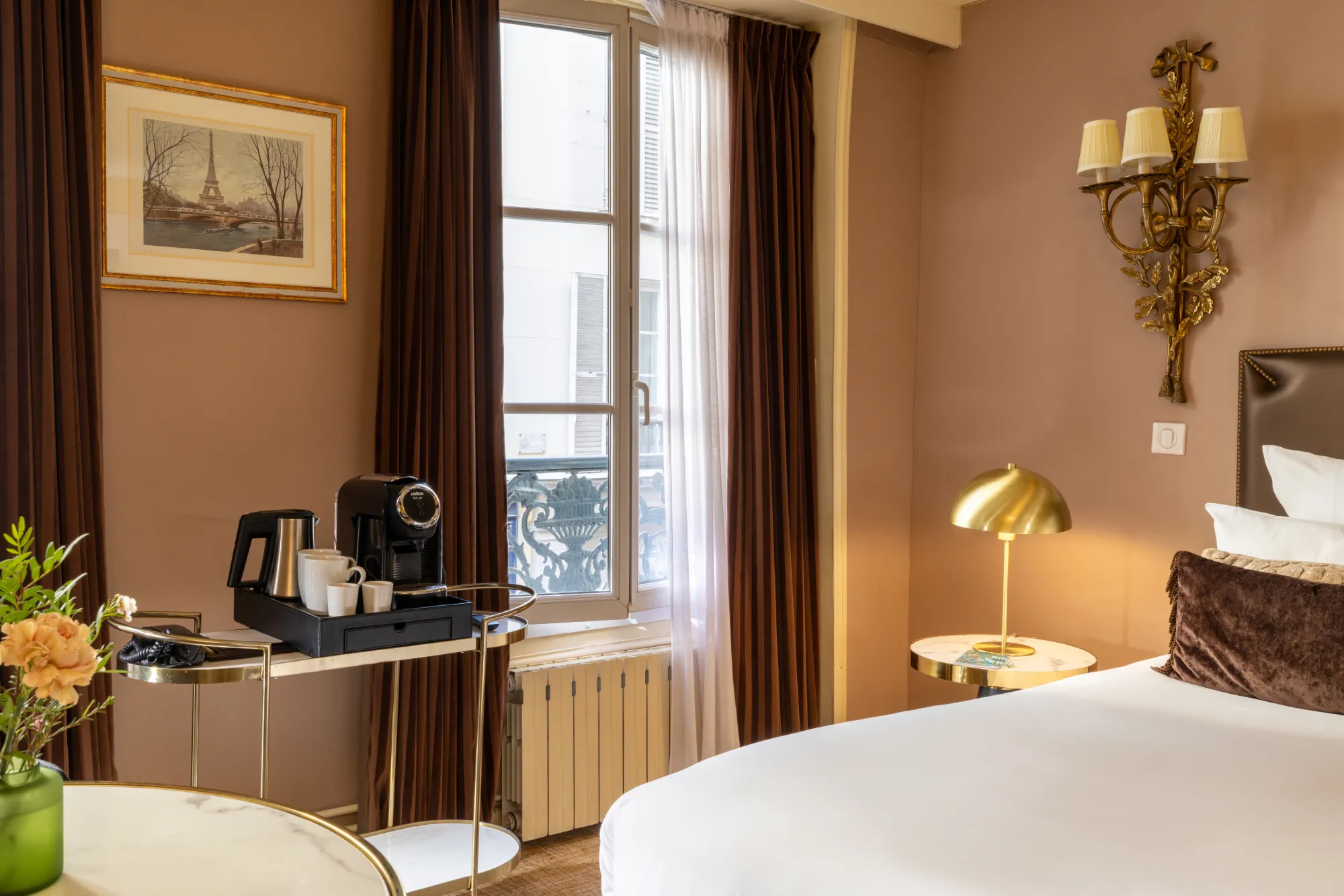 Bureau avec machine à café et fenêtre donnant sur les toits parisiens dans la chambre Deluxe