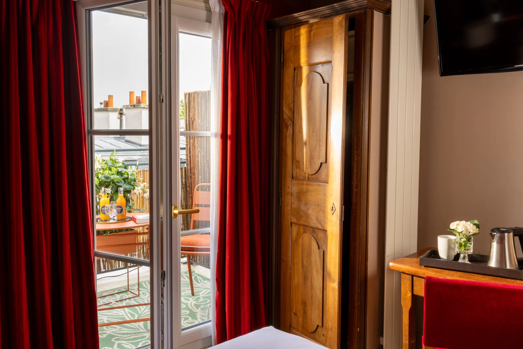 Porte de dressing en bois massif entre rideaux rouges et porte-fenêtre ouverte sur la terrasse, Chambre Terrasse