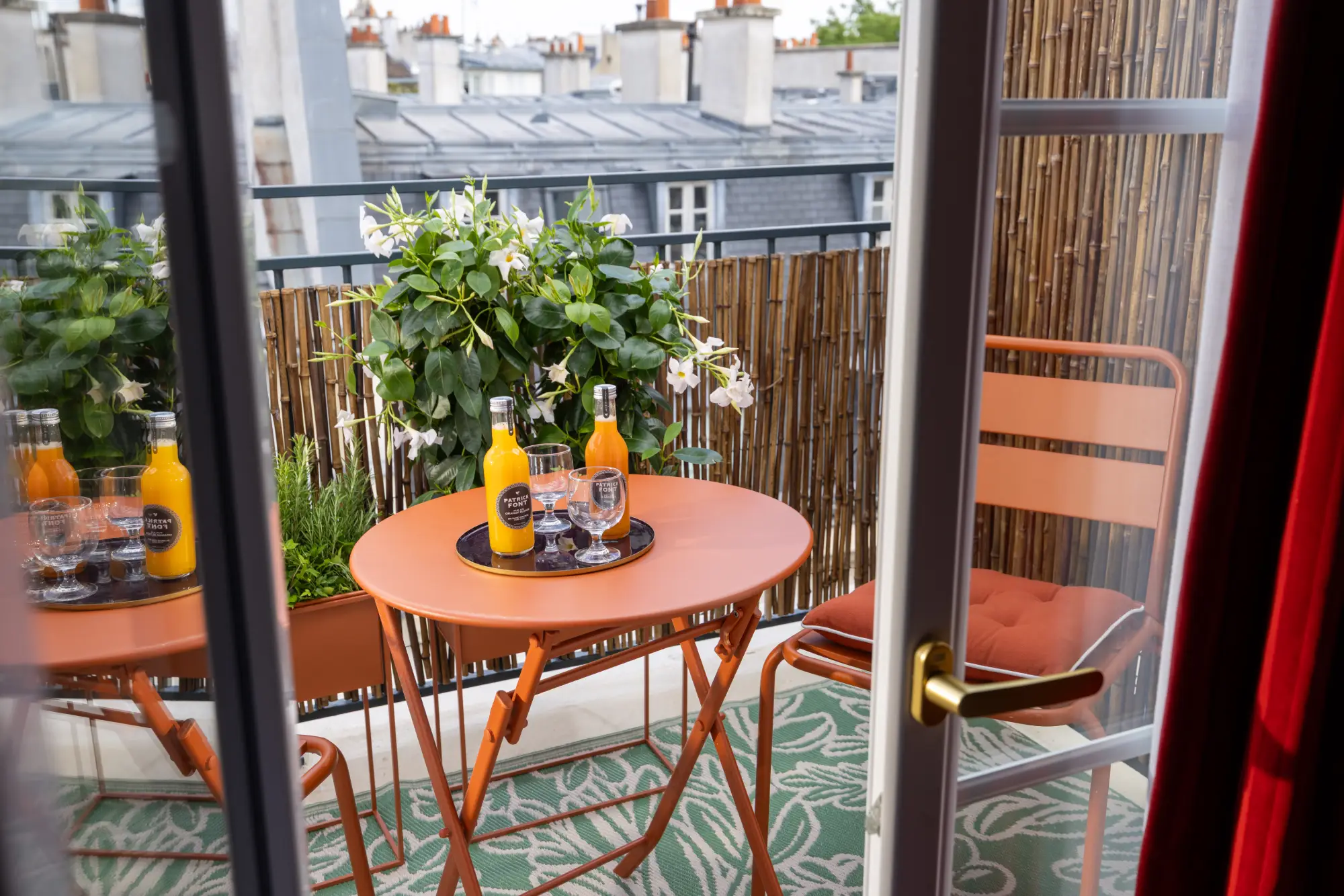Table et chaises bistrot en fer forgé sur une terrasse privative bordée de bambou, Hôtel des Deux Continents