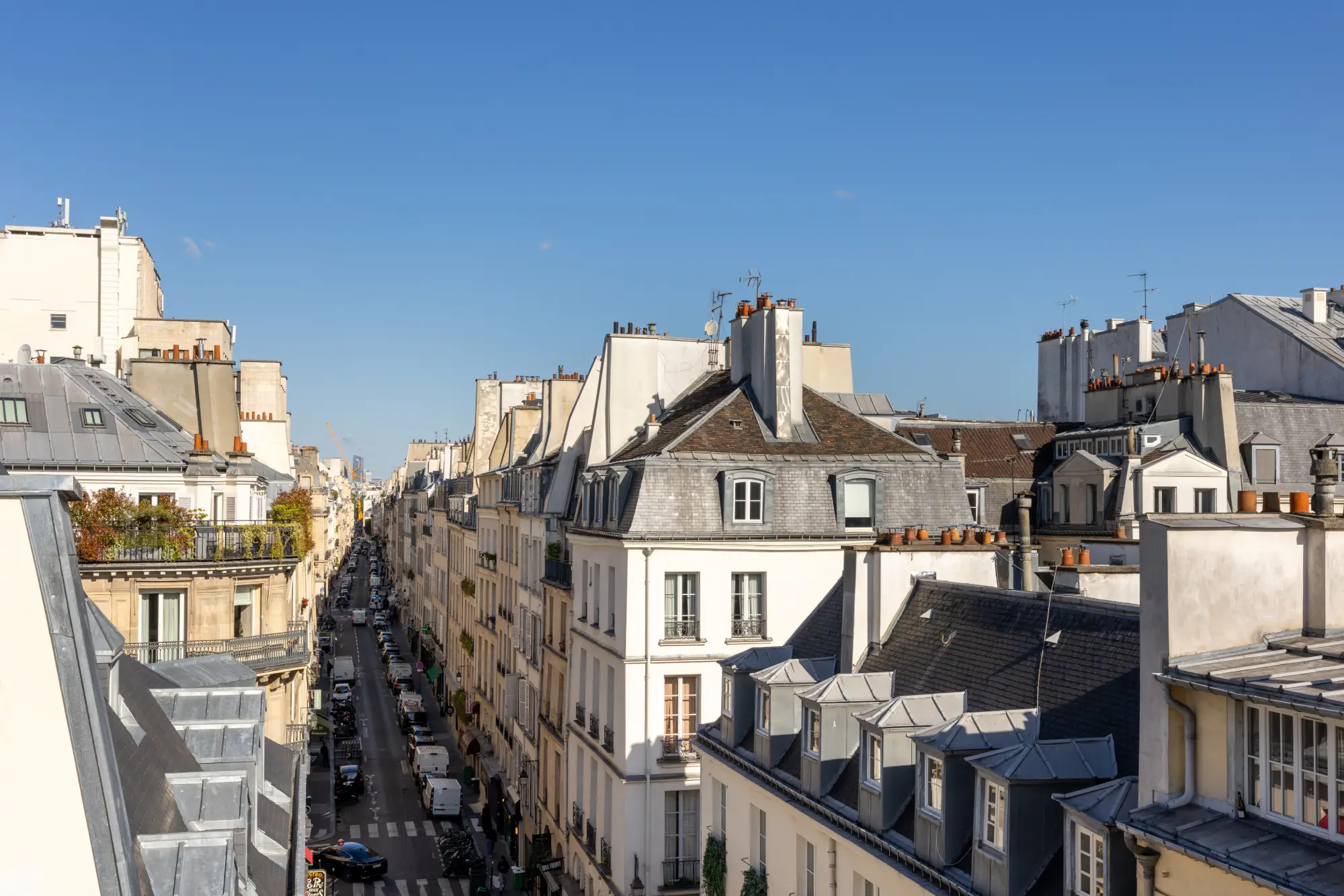 Vue sur les toits en zinc et façades haussmanniennes de Paris depuis la chambre avec terrasse