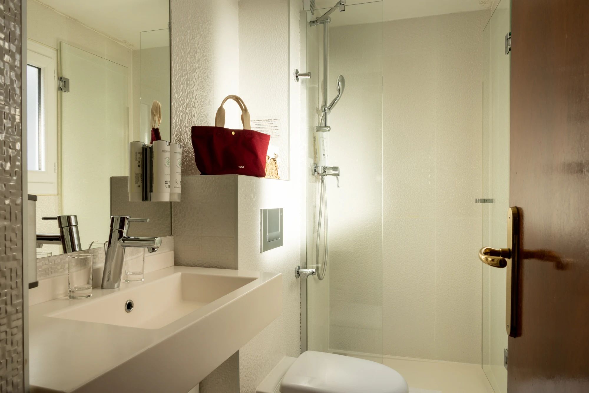 Douche vitrée, vasque et mosaïque dans la salle de bain de la chambre communicante