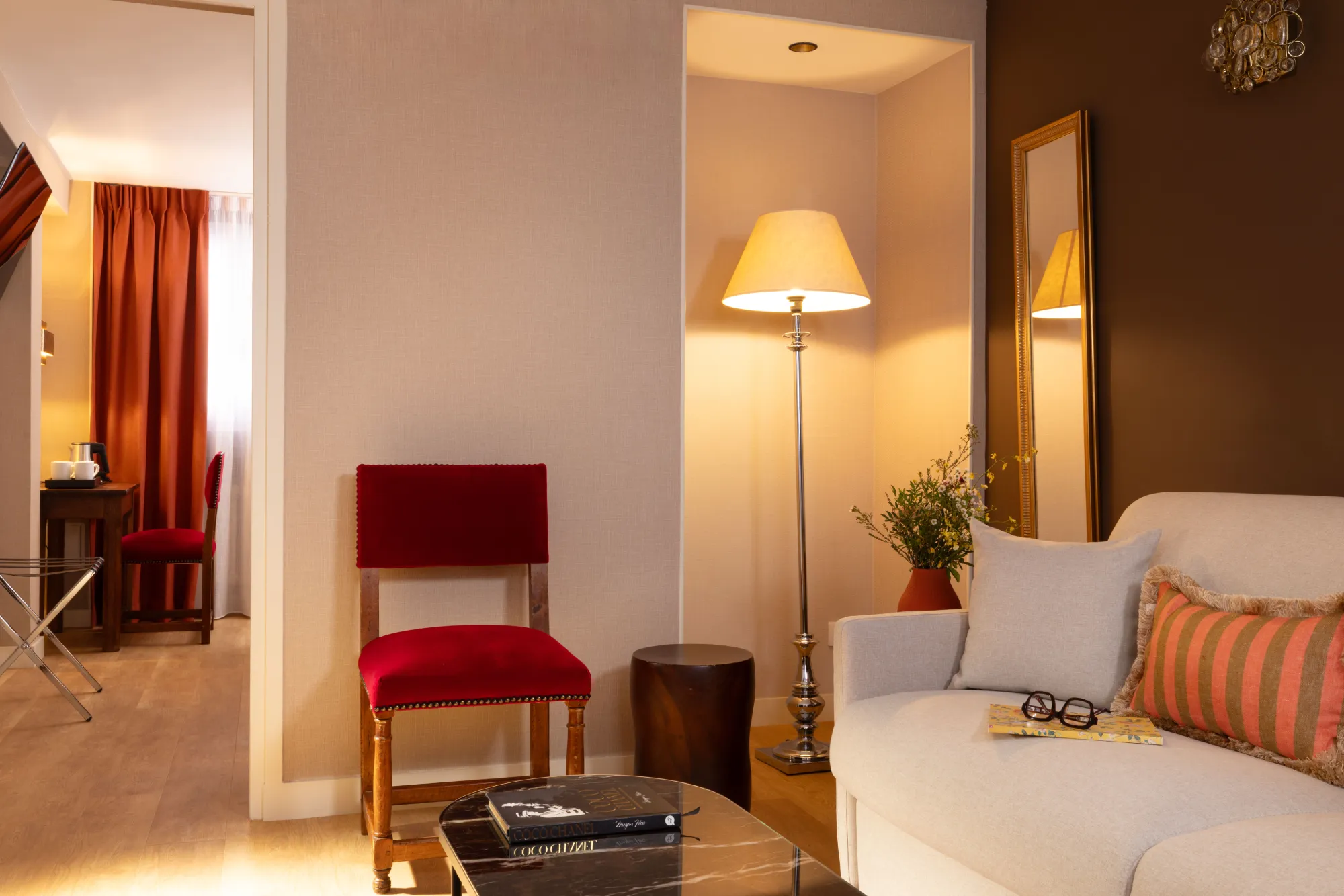 Coin salon avec canapé blanc, chaise rouge et lampadaire dans la Suite de l'Hôtel des Deux Continents