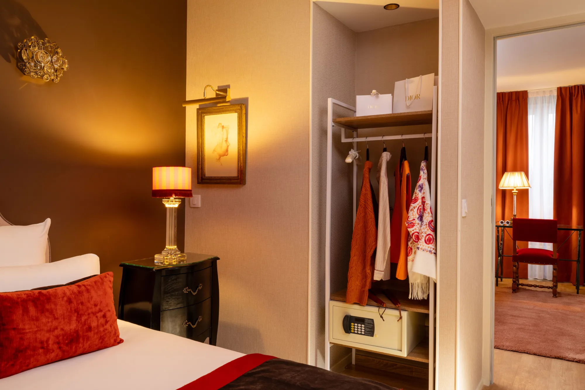 Penderie ouverte avec vêtements suspendus et valise dans le dressing de la Suite de l'Hôtel des Deux Continents