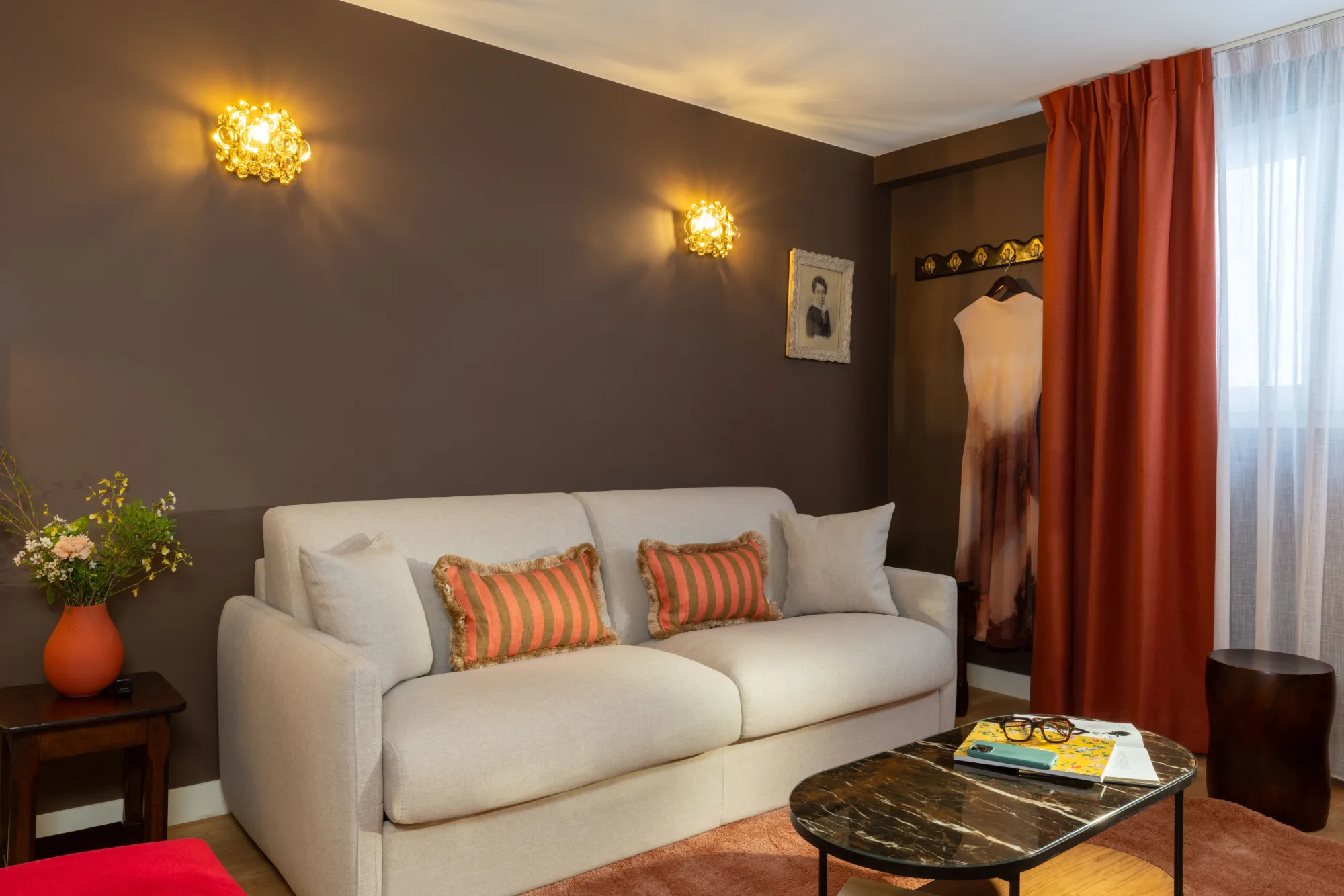Coin salon de la suite avec canapé beige et coussins orangés à l'Hôtel des Deux Continents