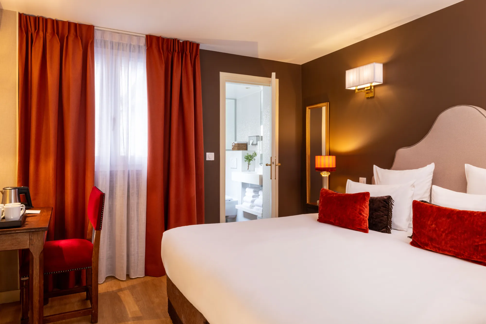 Lit double et rideaux rouges dans la chambre de la suite de l'Hôtel des Deux Continents