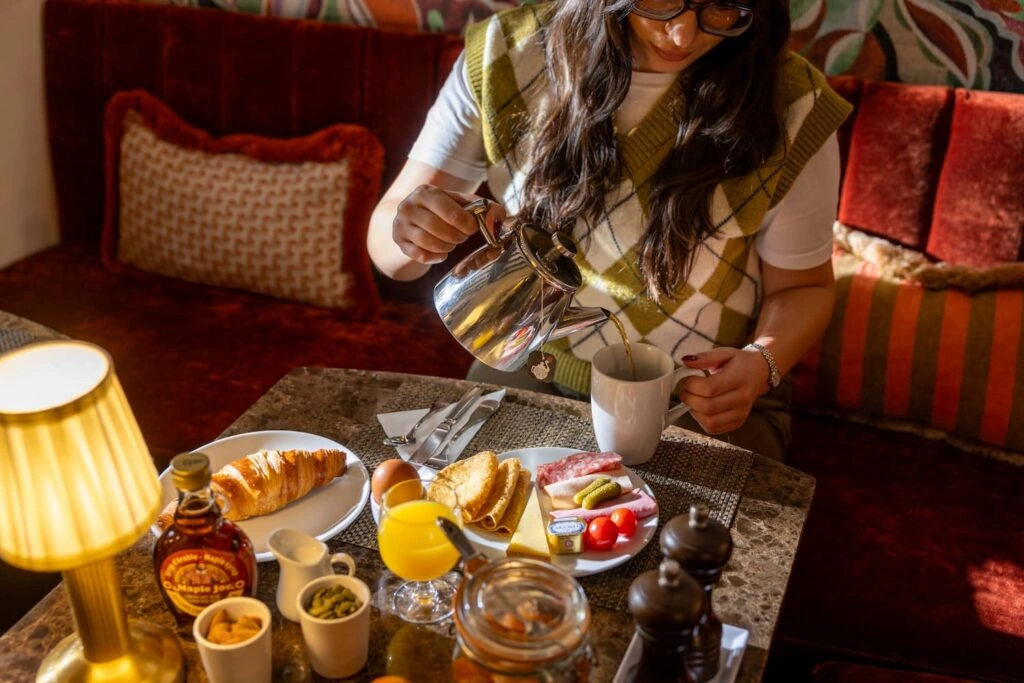 Personnel versant du café à une table de petit-déjeuner garnie de croissants et confitures
